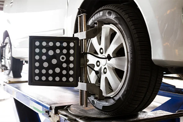 Alignment machine setup on front-left wheel of white SUV