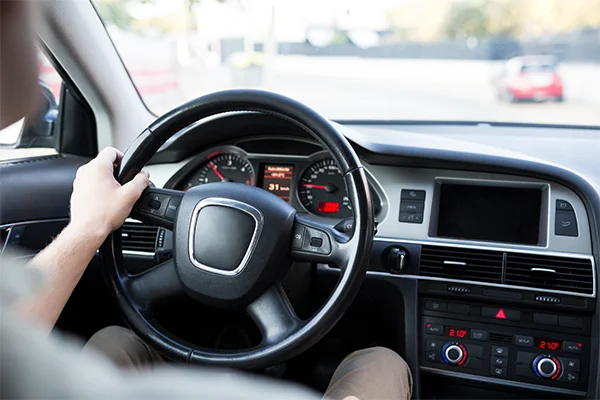 Man holding steering wheel in vehicle interior at an angle